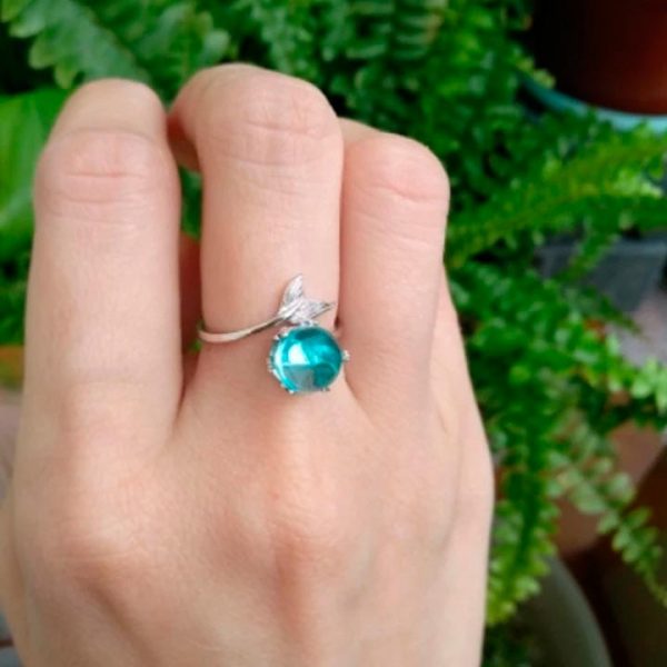 Imagen de anillo con cola de pez en un extremo y en el otro cristal turquesa en dedo