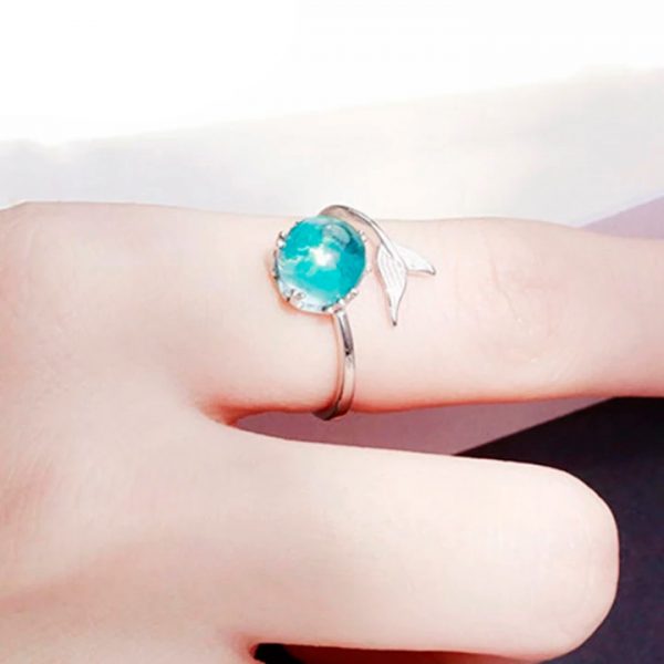 Imagen de anillo con cola de pez en un extremo y en el otro cristal turquesa en dedo